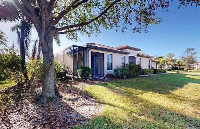 view of front of property with a tile roof, a front lawn, stucco siding, and a lanai