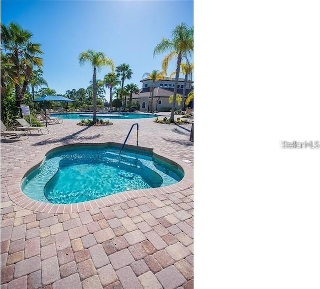 community pool featuring a hot tub and a patio area