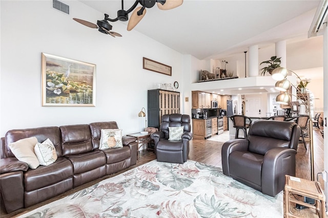 living room featuring ceiling fan, light hardwood / wood-style flooring, and high vaulted ceiling