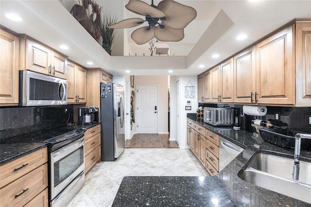 kitchen featuring stainless steel appliances, dark stone counters, sink, and tasteful backsplash