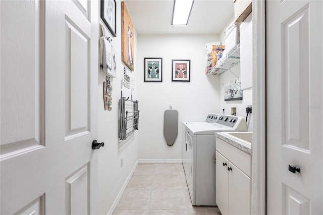 laundry room with washing machine and dryer, cabinets, and light tile patterned flooring