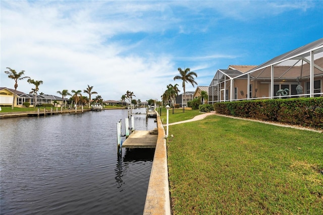 dock area featuring a water view, a lawn, and a lanai