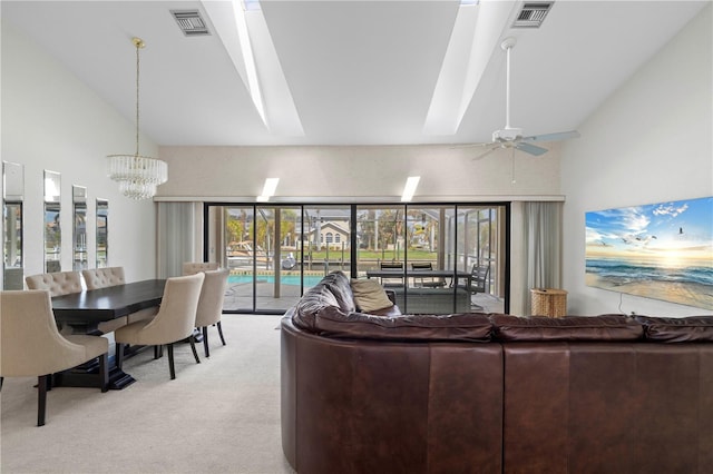 living room with a wealth of natural light, light carpet, ceiling fan with notable chandelier, and a skylight