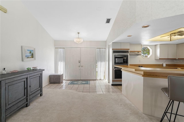 kitchen featuring double oven, decorative light fixtures, a chandelier, and light colored carpet