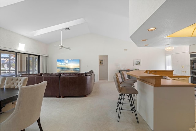 carpeted living room with lofted ceiling with skylight, sink, and ceiling fan