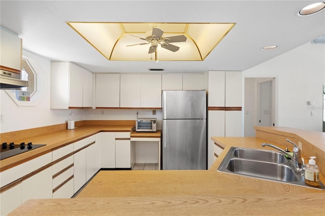 kitchen with sink, white cabinetry, and stainless steel refrigerator