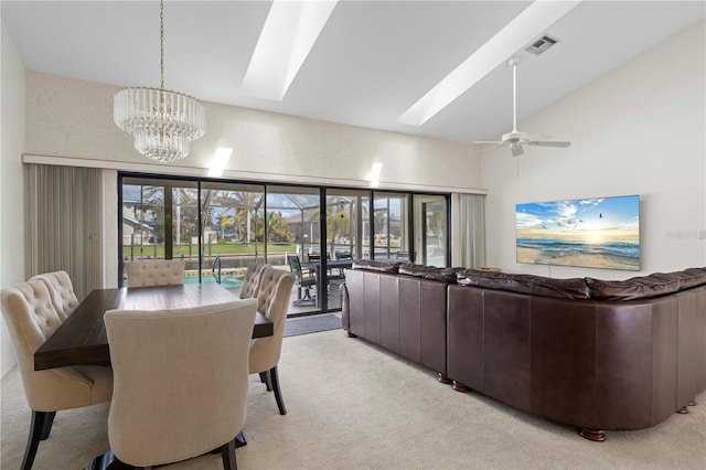 carpeted dining area featuring vaulted ceiling, plenty of natural light, and ceiling fan with notable chandelier