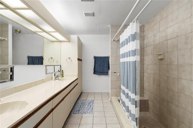 bathroom with vanity, walk in shower, a textured ceiling, and tile patterned flooring