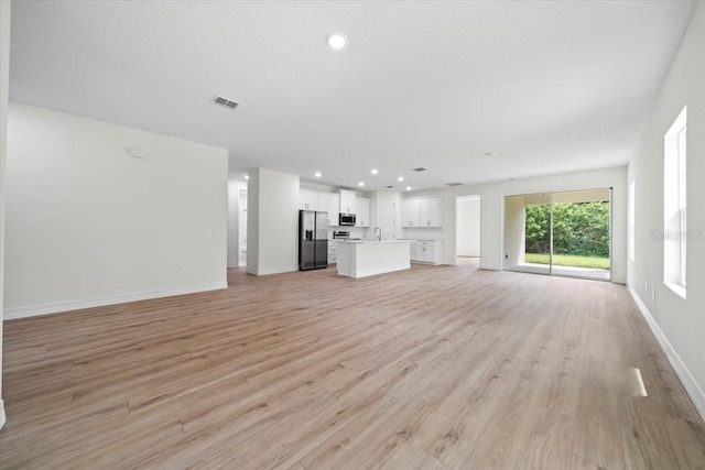 unfurnished living room featuring sink and light hardwood / wood-style flooring