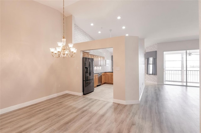 interior space with refrigerator with ice dispenser, light wood-type flooring, high vaulted ceiling, hanging light fixtures, and stainless steel dishwasher