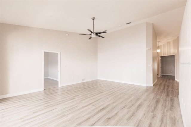 unfurnished room with a towering ceiling, ceiling fan, and light wood-type flooring