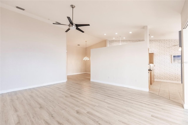 unfurnished room with ceiling fan with notable chandelier, light hardwood / wood-style flooring, and vaulted ceiling