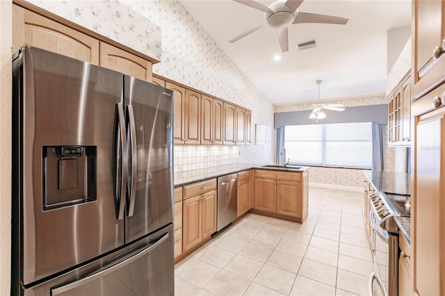 kitchen with stainless steel appliances, vaulted ceiling, kitchen peninsula, sink, and light tile patterned flooring