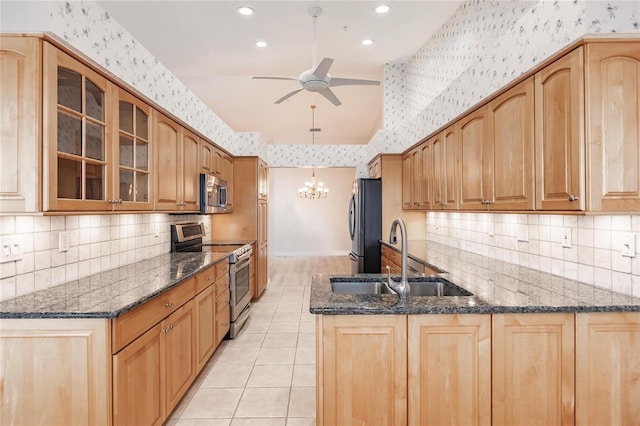 kitchen with kitchen peninsula, dark stone countertops, sink, and appliances with stainless steel finishes