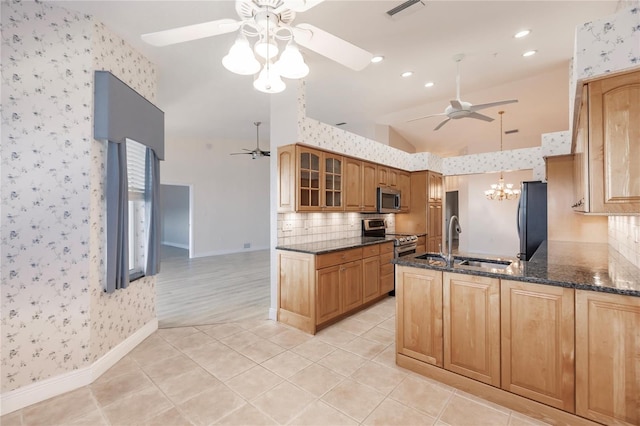 kitchen with stainless steel appliances, dark stone counters, light tile patterned floors, sink, and vaulted ceiling