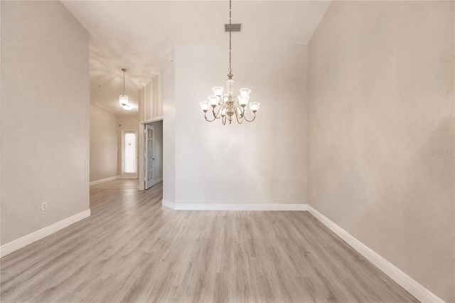 unfurnished room with an inviting chandelier and light wood-type flooring