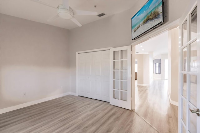 unfurnished bedroom with ceiling fan, a closet, light wood-type flooring, and french doors