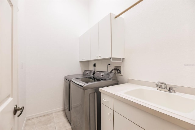 washroom with cabinets, washing machine and dryer, sink, and light tile patterned floors