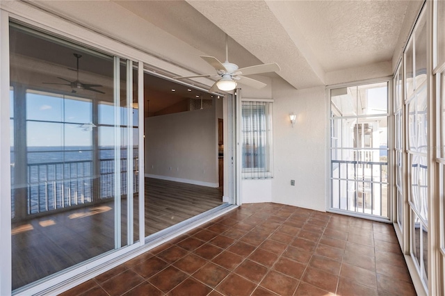 unfurnished sunroom with a water view and ceiling fan