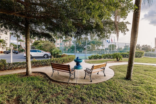 view of home's community with a lawn and tennis court