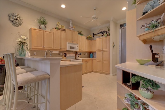 kitchen with kitchen peninsula, ornamental molding, a kitchen bar, light tile patterned floors, and white appliances