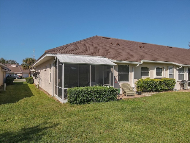 rear view of property featuring a yard and a sunroom