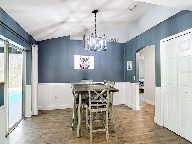 3316 Kacher Rd, North Port, FL 34288 - dining space with arched walkways, lofted ceiling, a chandelier, and wood finished floors