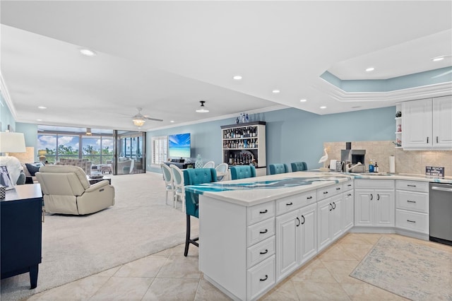 kitchen with white cabinetry, crown molding, kitchen peninsula, and ceiling fan