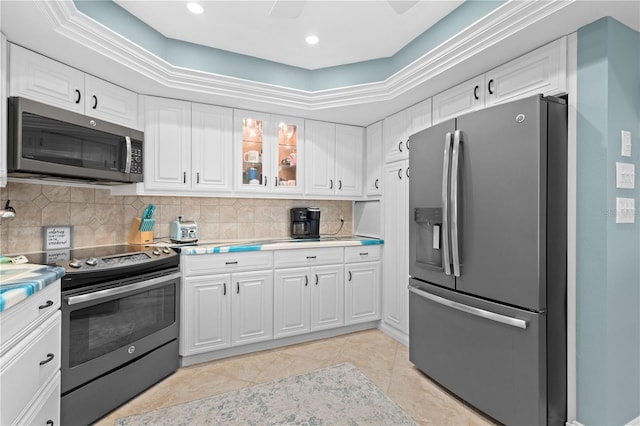 kitchen featuring backsplash, white cabinets, stainless steel appliances, and a tray ceiling