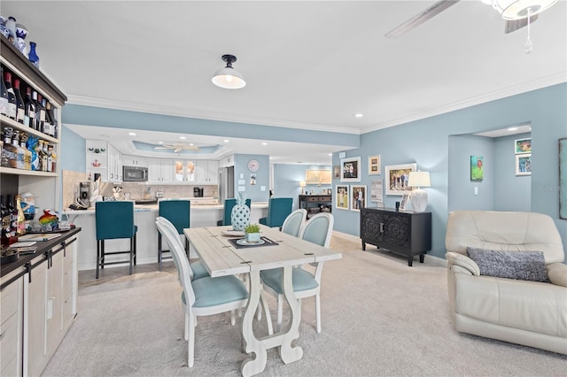 dining space featuring ceiling fan, ornamental molding, and light colored carpet