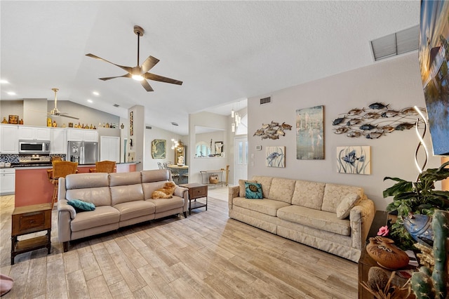 living room featuring a textured ceiling, light hardwood / wood-style floors, lofted ceiling, and ceiling fan