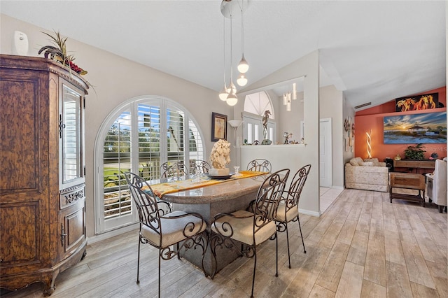 dining space with light hardwood / wood-style floors, lofted ceiling, and a notable chandelier