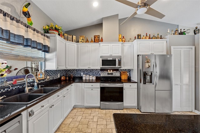 kitchen with stainless steel appliances, white cabinets, sink, and vaulted ceiling