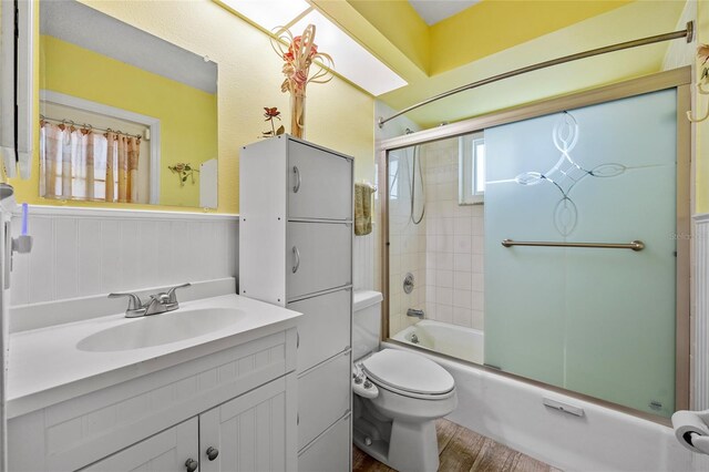 full bathroom featuring shower / bath combination with glass door, toilet, vanity, and wood-type flooring