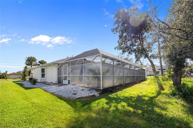 rear view of property with glass enclosure and a yard