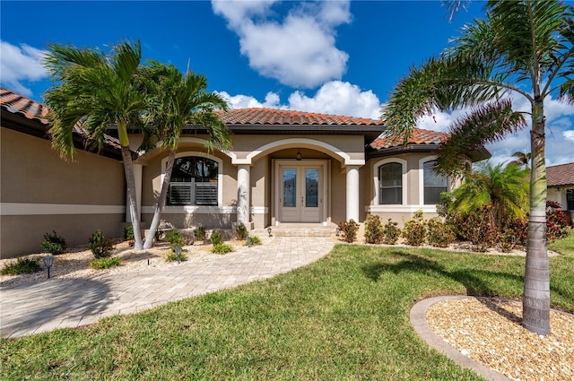 mediterranean / spanish house featuring a porch, a front yard, and french doors