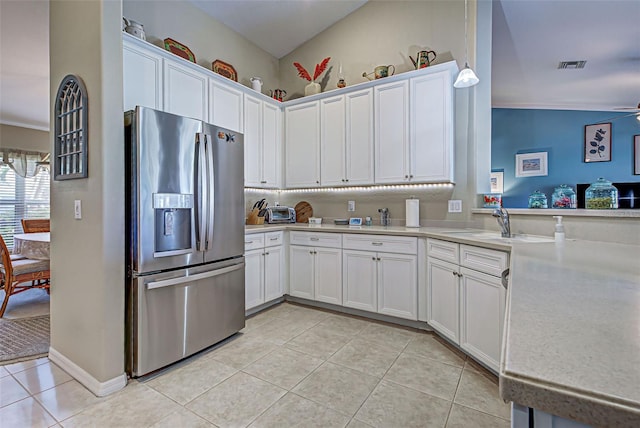 kitchen with lofted ceiling, stainless steel fridge, ceiling fan, light tile patterned floors, and white cabinetry