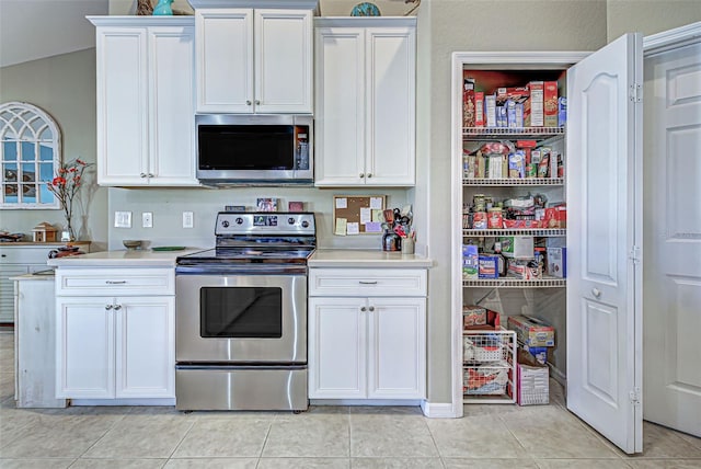 kitchen with stainless steel appliances, light tile patterned flooring, and white cabinets