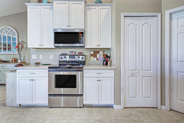 kitchen with light tile patterned flooring, white cabinetry, stainless steel appliances, and vaulted ceiling