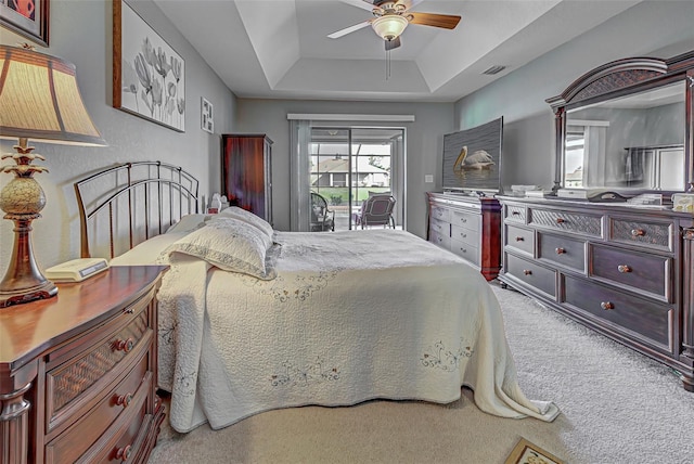 bedroom featuring ceiling fan, carpet, and a tray ceiling