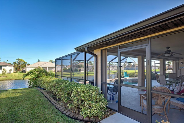 view of patio featuring a water view, glass enclosure, and ceiling fan