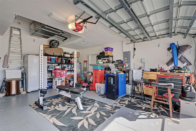 garage featuring white fridge, a workshop area, a garage door opener, and electric panel