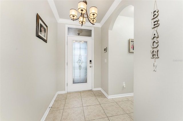 tiled foyer featuring crown molding and an inviting chandelier