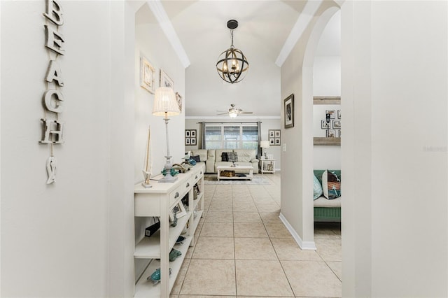 hall with a notable chandelier, light tile patterned floors, and crown molding