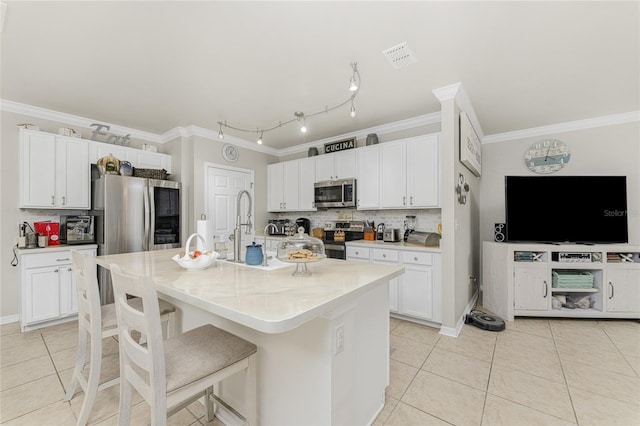 kitchen featuring stainless steel appliances, white cabinetry, a kitchen island with sink, and decorative backsplash