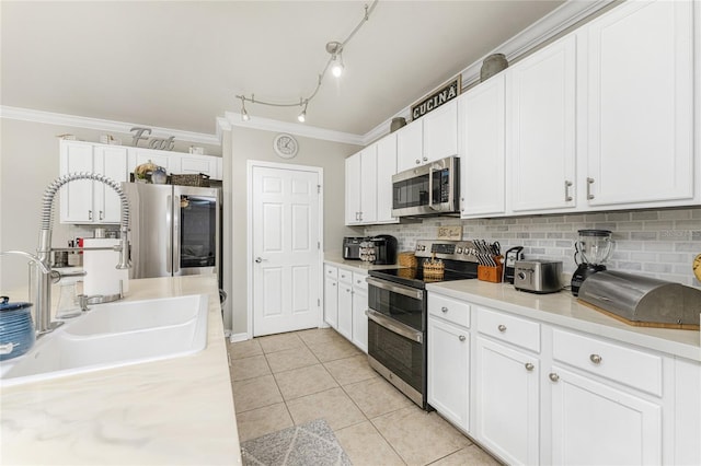 kitchen featuring white cabinets, stainless steel appliances, ornamental molding, and light tile patterned floors