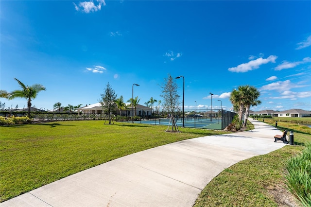 view of home's community with a lawn and tennis court