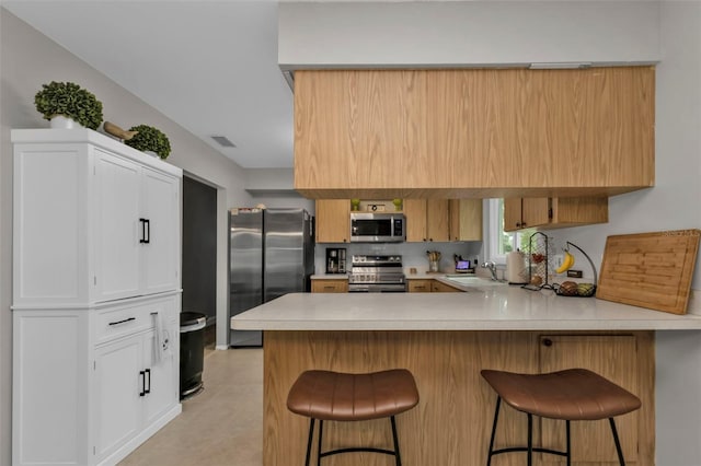 kitchen with kitchen peninsula, sink, a kitchen bar, and stainless steel appliances