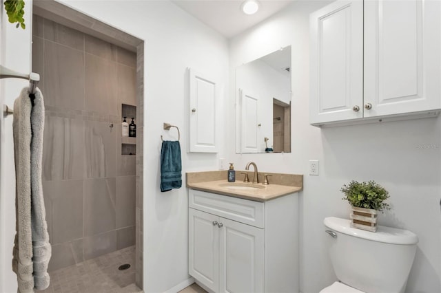 bathroom featuring tiled shower, toilet, and vanity