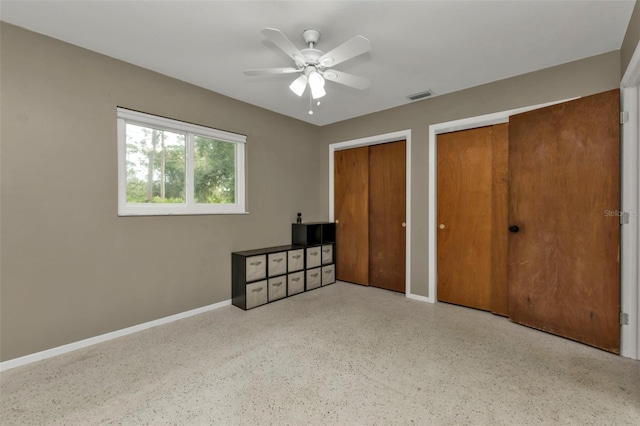 unfurnished bedroom featuring two closets and ceiling fan